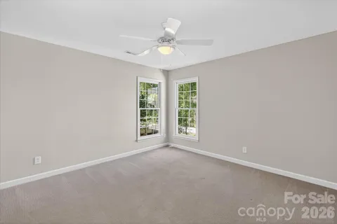 an empty room with windows and ceiling fan