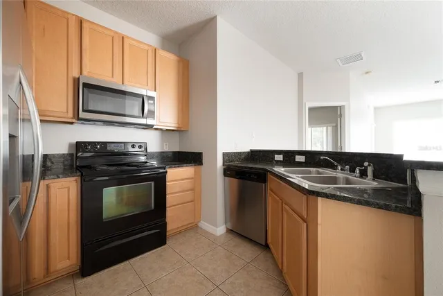 a kitchen with granite countertop a sink stove and microwave