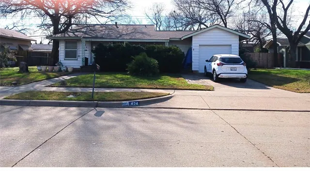 a front view of a house with a garden and trees