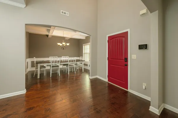 a dining room with wooden floor a chandelier a wooden table and chairs