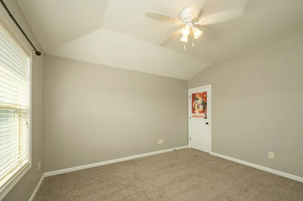 an empty room with chandelier fan and windows