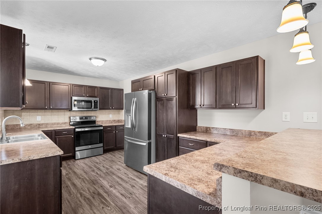 186 Scanner Court Raeford, NC 28376 - Photo 16 of 49 a kitchen with granite countertop wooden cabinets a refrigerator and a sink