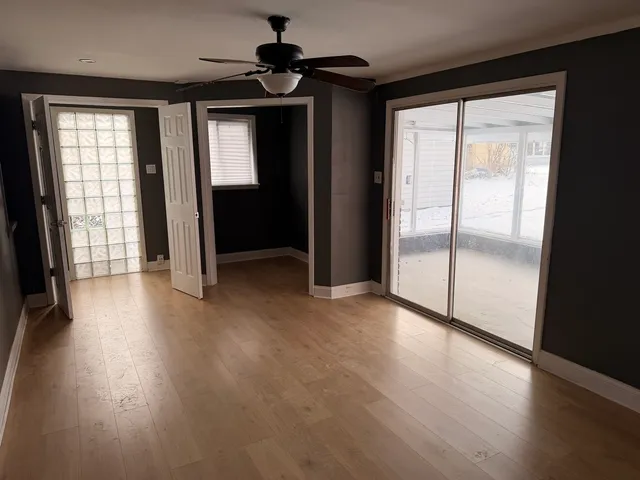a view of empty room with wooden floor and fan