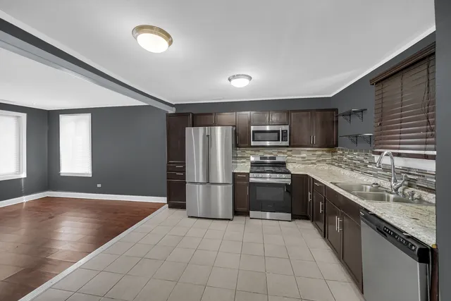 a large kitchen with stainless steel appliances granite countertop a refrigerator and a stove top oven