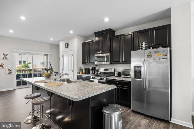 a kitchen with stainless steel appliances granite countertop a sink stove refrigerator and cabinets