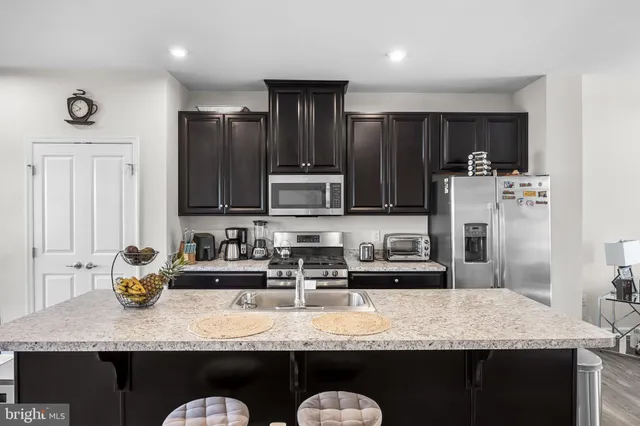a kitchen with stainless steel appliances granite countertop a sink refrigerator and cabinets
