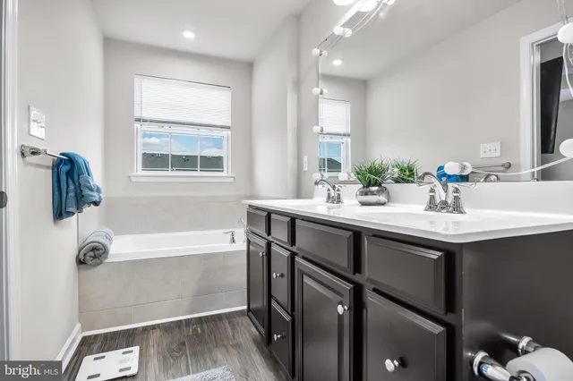 a bathroom with a sink double vanity granite tub shower and mirror