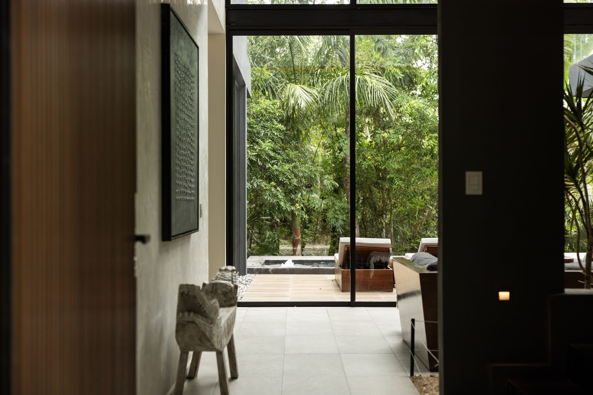 6 Country Club, Unit 4 Nome, TX 77629 - Photo 30 of 45 The moment you step through the front entrance, your eyes are immediately drawn across the sleek interior gallery toward a spectacular, floor-to-ceiling framed view of the private courtyard pool and dense tropical jungle.
