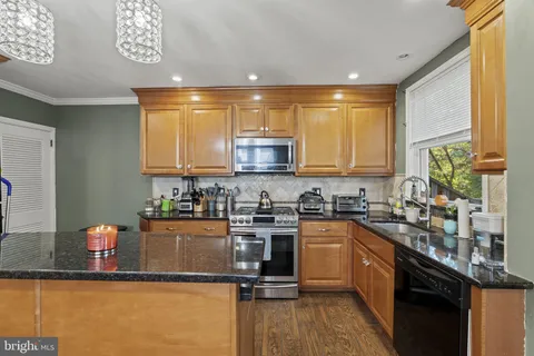a kitchen with granite countertop a stove a sink dishwasher and a microwave oven with wooden floor