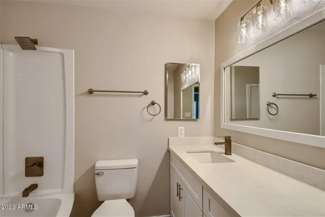 a bathroom with a toilet sink vanity and mirror