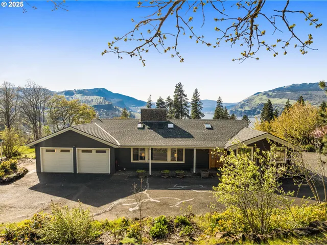 a front view of a house with a yard and mountain view in back