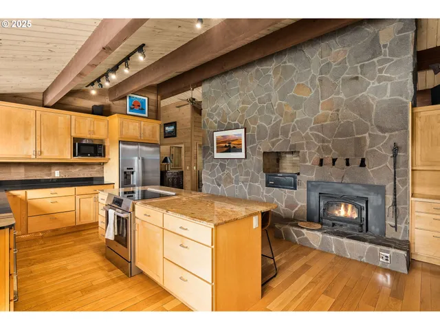 a open kitchen with granite countertop a stove top oven a sink dishwasher and a fireplace with wooden floor
