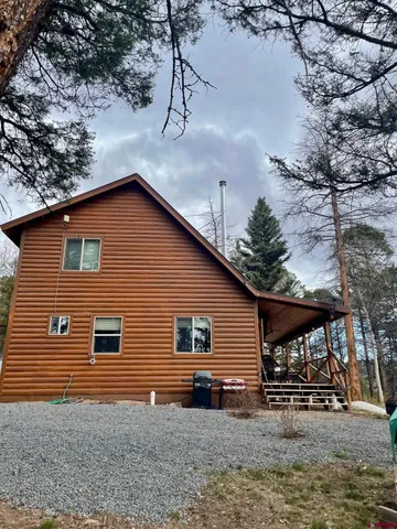 a backyard of a house with table and chairs under an umbrella