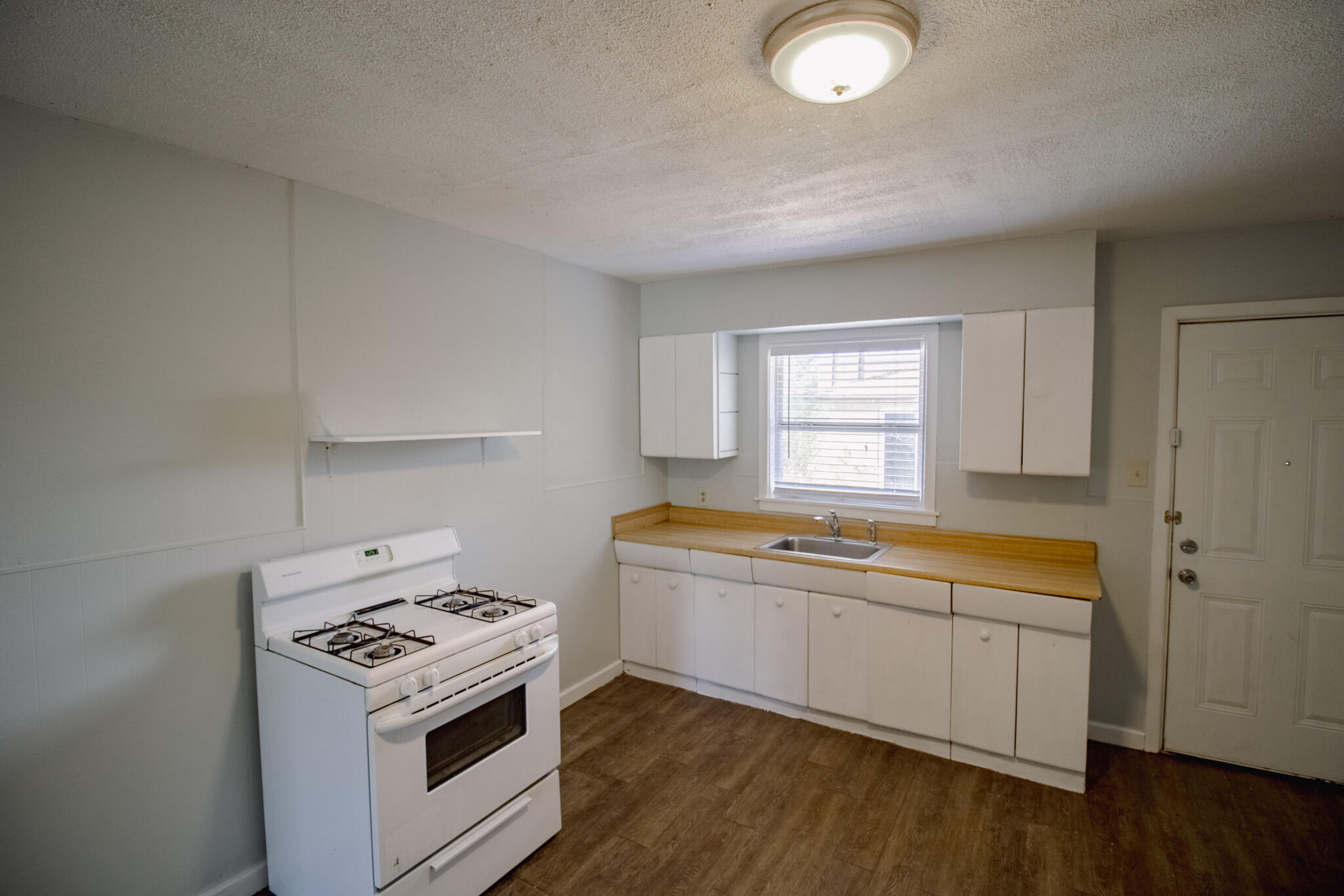 2906 43rd Street, Unit B Lubbock, TX 79413 - Photo 6 of 8 a kitchen that has a stove and wooden floor