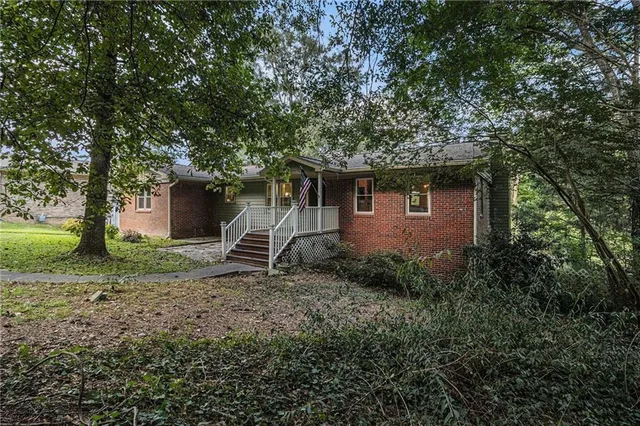 a backyard of a house with plants and large tree