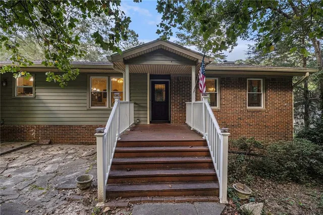a front view of a house with wooden stairs and a large tree