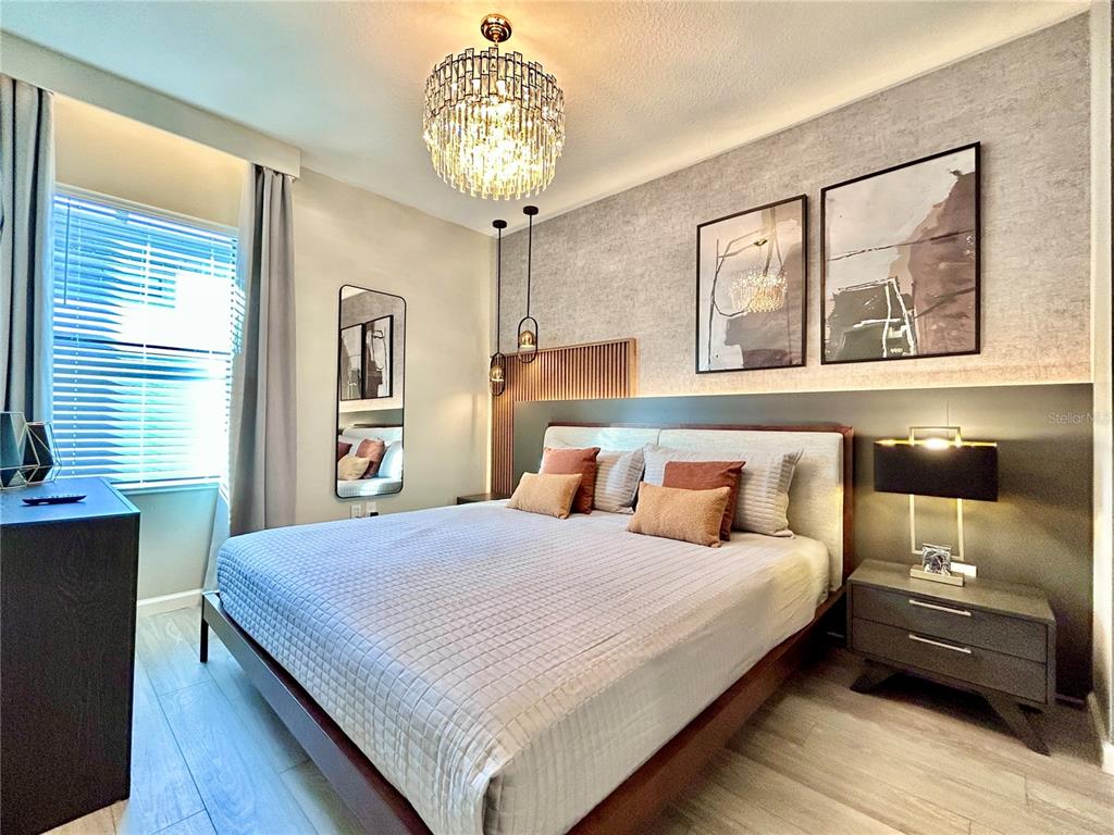 6271 Sand Skipper Road Orlando, FL 32821 - Photo 22 of 46 a bedroom with a large bed and a chandelier