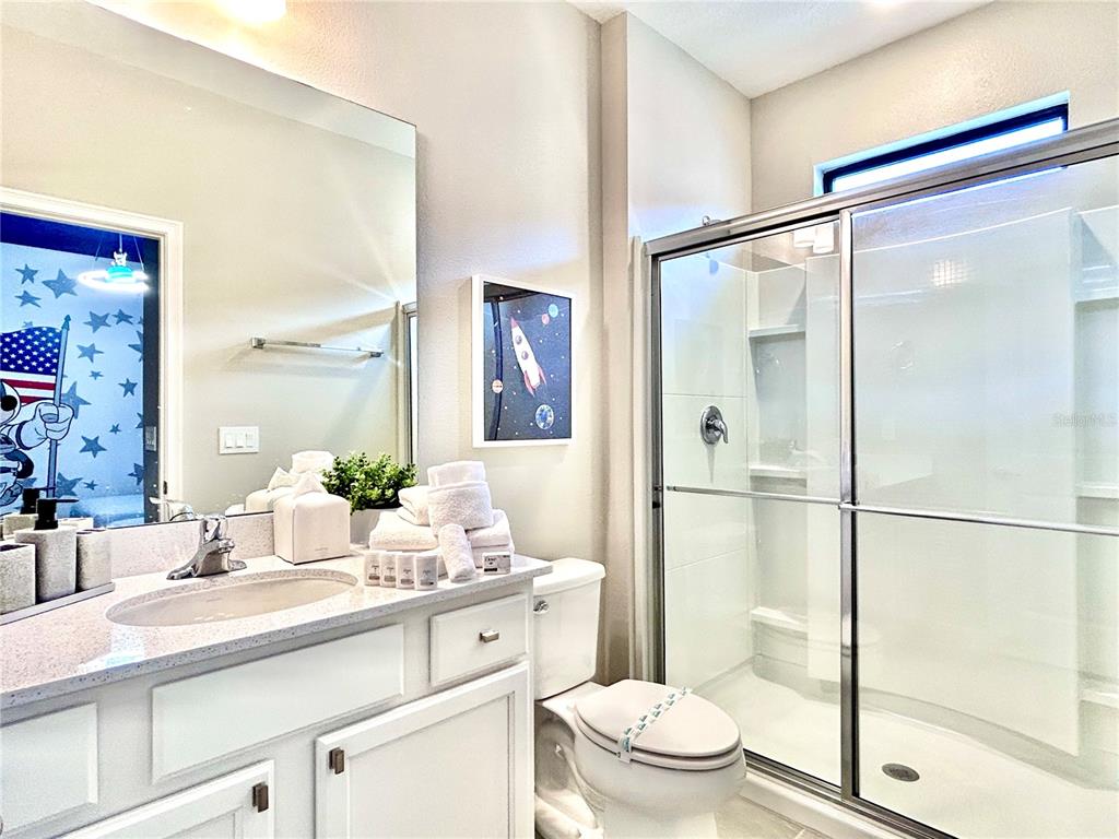 6271 Sand Skipper Road Orlando, FL 32821 - Photo 31 of 46 a bathroom with a granite countertop sink mirror toilet and shower