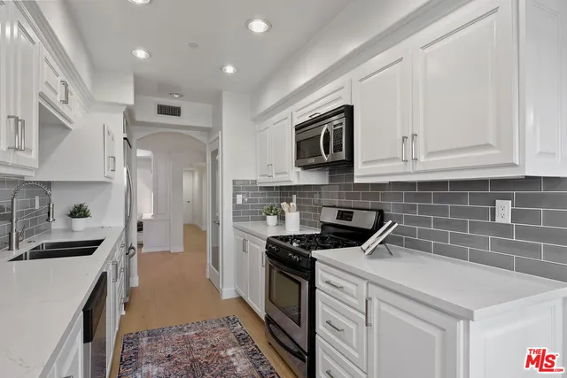 a kitchen with stainless steel appliances granite countertop a stove a sink and a microwave
