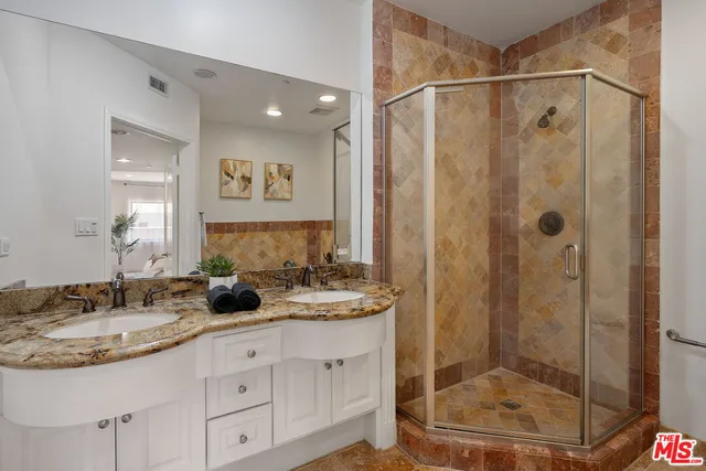 a bathroom with a granite countertop sink a mirror a shower and a mirror