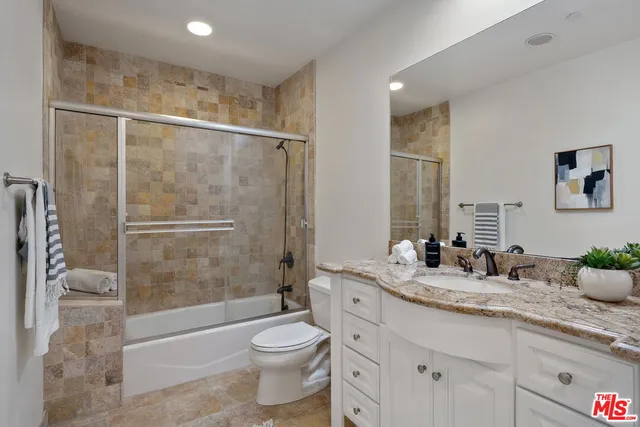a bathroom with a granite countertop sink toilet and shower