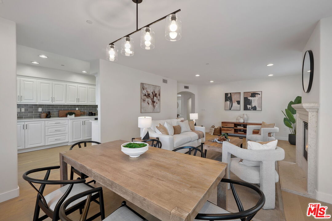 1629 Armacost Avenue, Unit 101 Los Angeles, CA 90025 - Photo 9 of 26 a kitchen with a dining table chairs sink and white cabinets