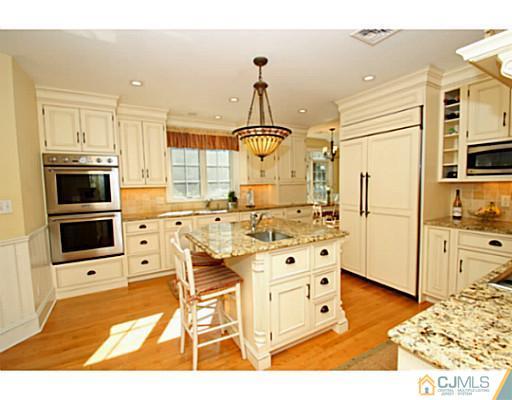 33 Edgewood Road Edison, NJ 08820 - Photo 7 of 25 a kitchen with stainless steel appliances kitchen island granite countertop a stove a refrigerator and white cabinets with wooden floor