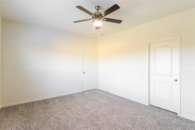 an empty room with a ceiling fan and a window