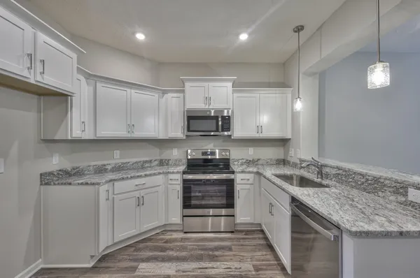 a kitchen with granite countertop a sink stainless steel appliances and white cabinets
