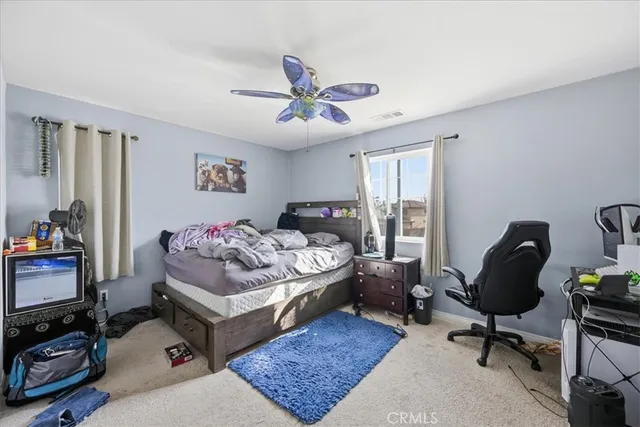 a bedroom with a bed a desk and chair with a bookshelf