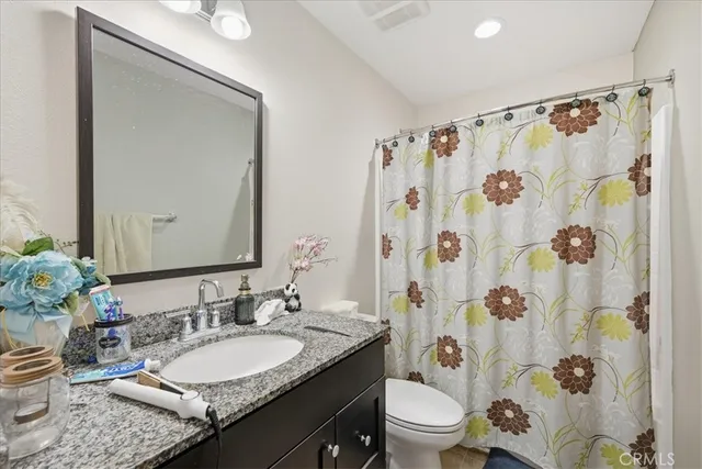 a bathroom with a granite countertop sink toilet a mirror a shower curtain and a sink