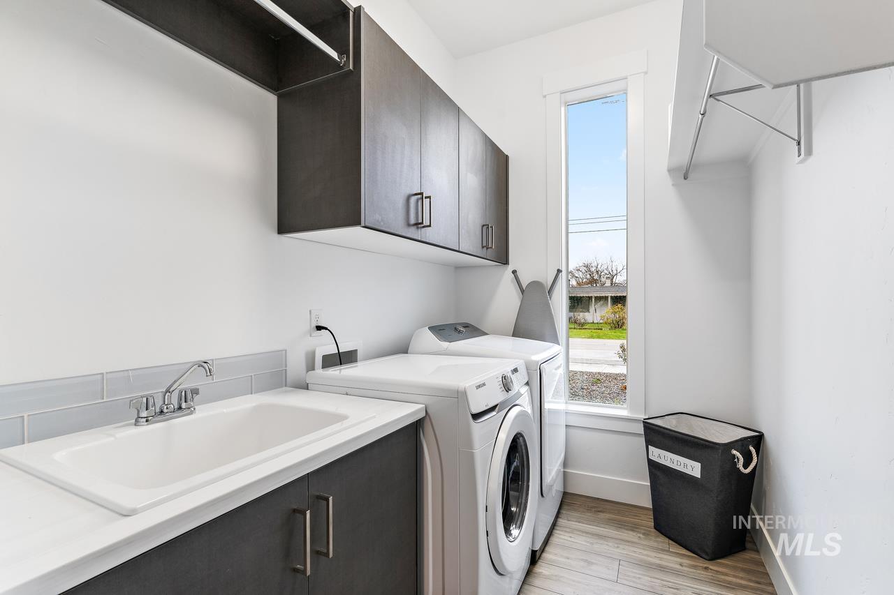 599 West Warren Street Boise, ID 83706 - Photo 27 of 41 Dedicated laundry room featuring wood-finish flooring, a utility sink with a stone-finish countertop, dark wood-finish cabinetry, and a vertical window