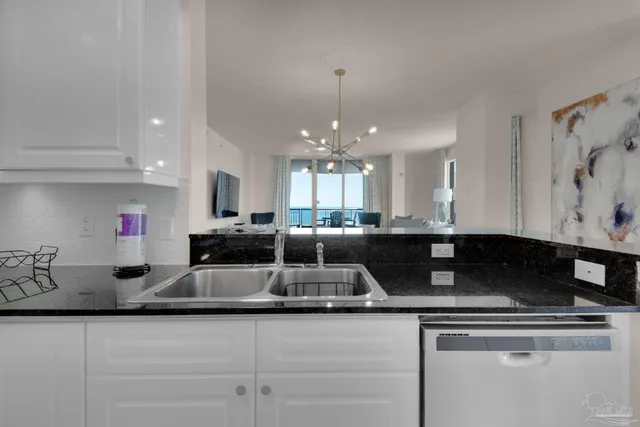 a kitchen with kitchen island granite countertop a sink white cabinets and stainless steel appliances