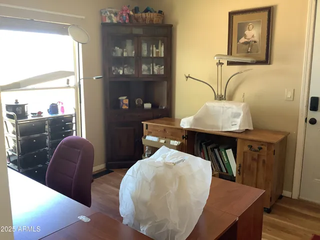 a bedroom with a bed and dresser with wooden floor