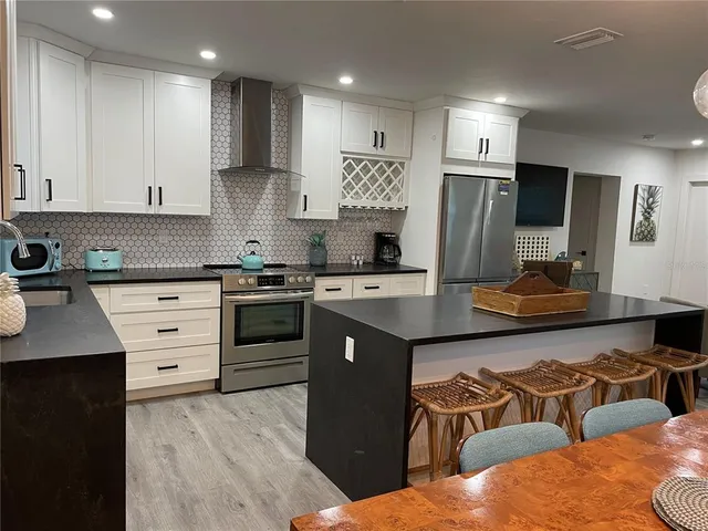 a kitchen with stainless steel appliances kitchen island granite countertop a refrigerator and a stove top oven