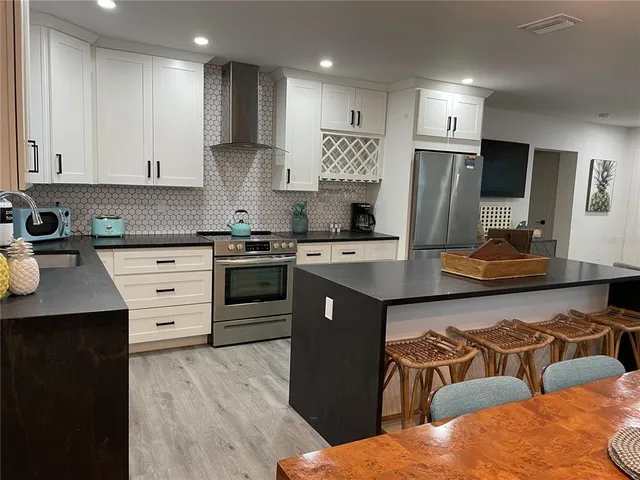 a kitchen with stainless steel appliances kitchen island granite countertop a stove a sink a refrigerator and a microwave