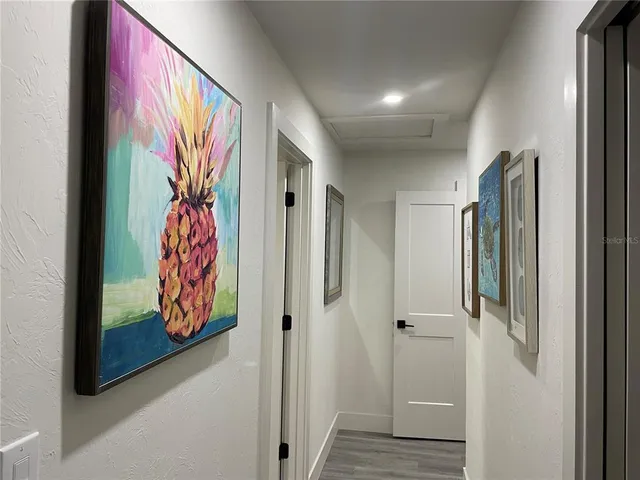a view of a hallway with wooden floor and paintings on the wall
