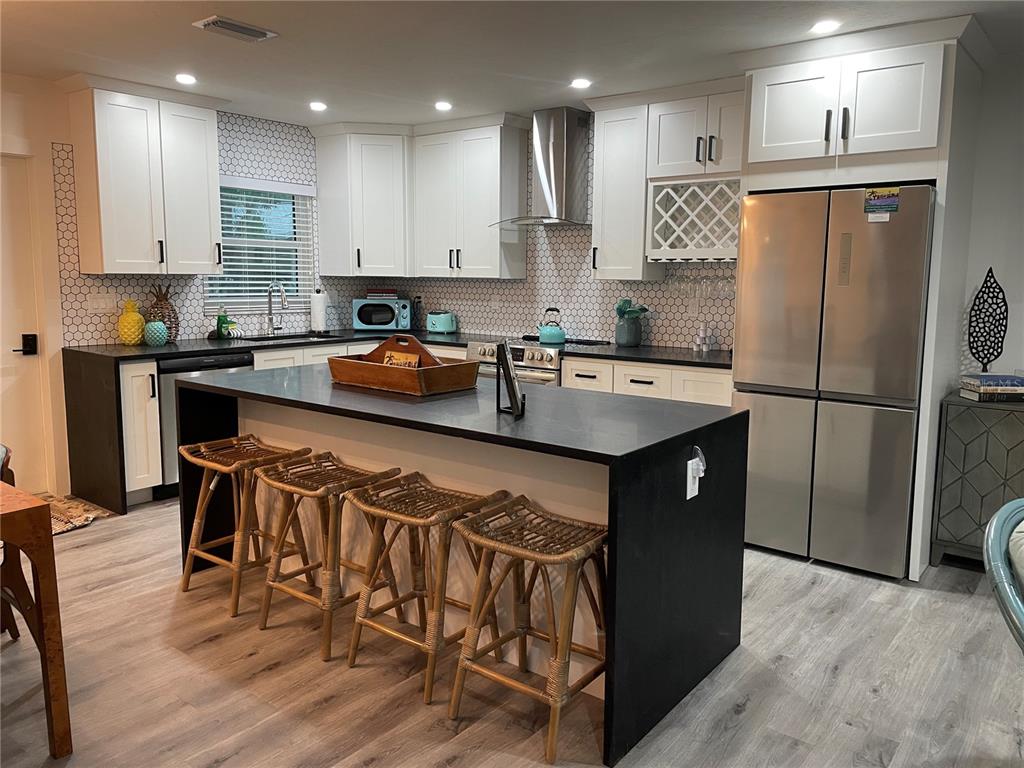 1920 Morrill Street, Unit PINEAPPLE Sarasota, FL 34236 - Photo 10 of 37 a kitchen with stainless steel appliances granite countertop a refrigerator a stove a sink a dining table and chairs with wooden floor