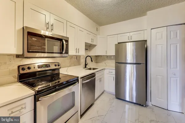 a kitchen with stainless steel appliances granite countertop a refrigerator stove a microwave and cabinets