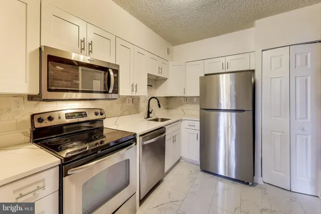 a kitchen with stainless steel appliances granite countertop a refrigerator stove a microwave and cabinets