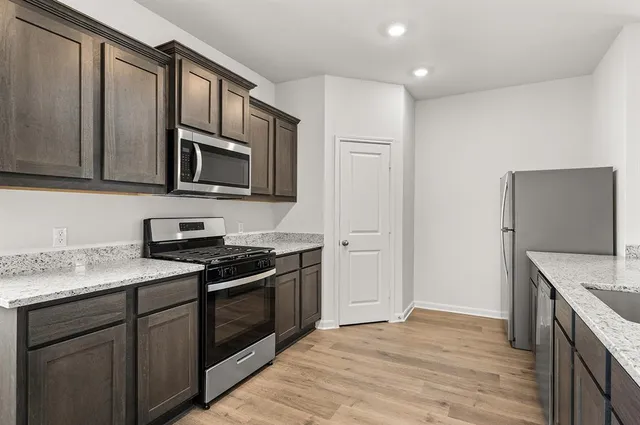 a view of kitchen with microwave a stove a sink dishwasher and a refrigerator with wooden floor