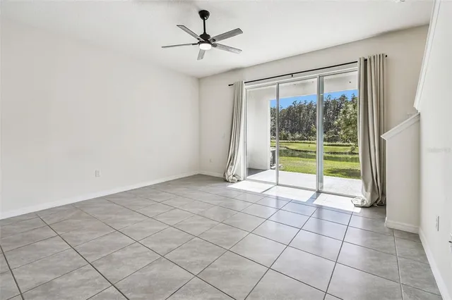 a view of an empty room and window a ceiling fan