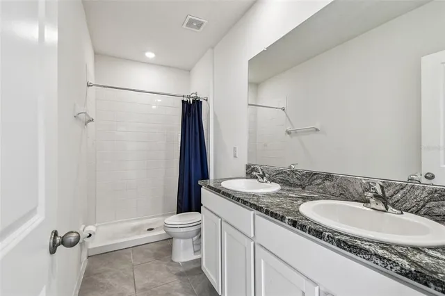 a bathroom with a granite countertop sink a toilet a mirror and shower