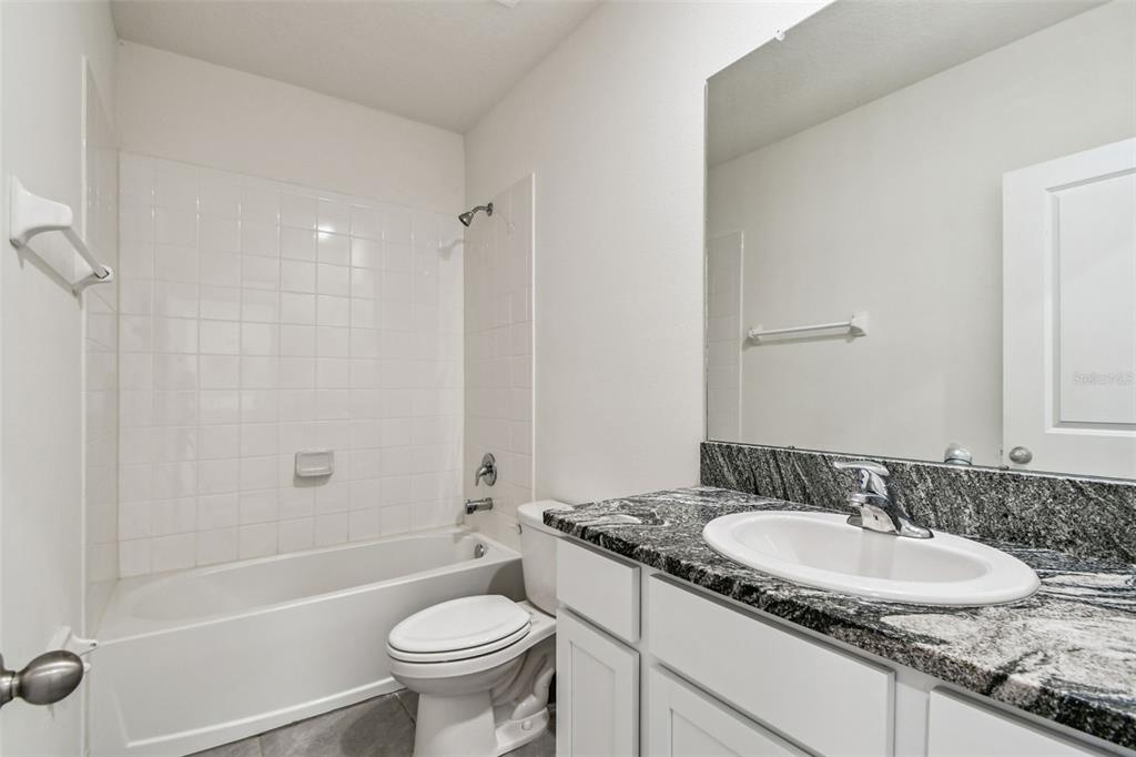 32173 Turtle Grace Loop Wesley Chapel, FL 33545 - Photo 27 of 41 a bathroom with a granite countertop sink a toilet a mirror and shower