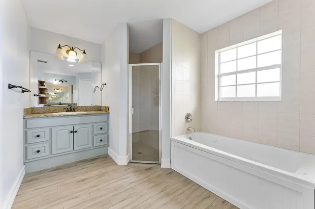 a spacious bathroom with double vanity a a bathtub a shower a sink and mirror