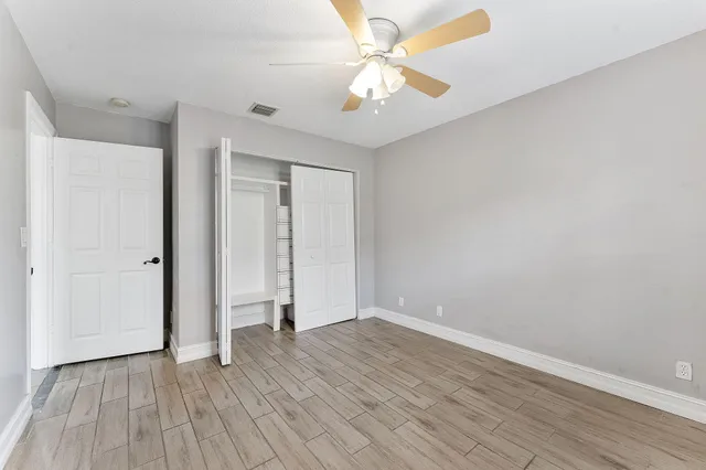 an empty room with wooden floor and ceiling fan
