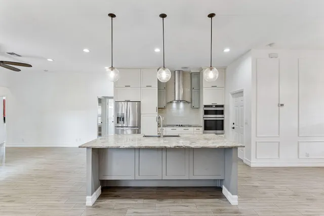 a kitchen with kitchen island a counter space stainless steel appliances and a ceiling fan