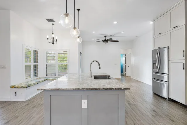 a kitchen with granite countertop a sink cabinets a refrigerator and wooden floor