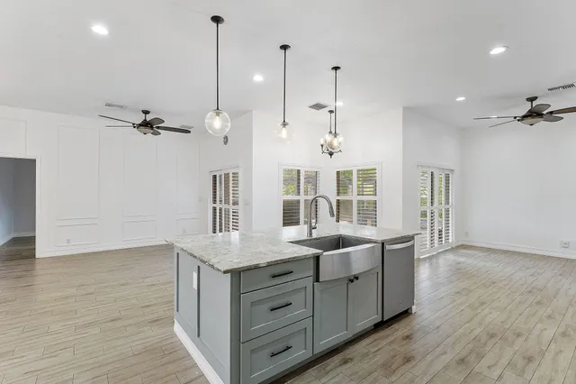 a kitchen with a sink chandelier and wooden floor