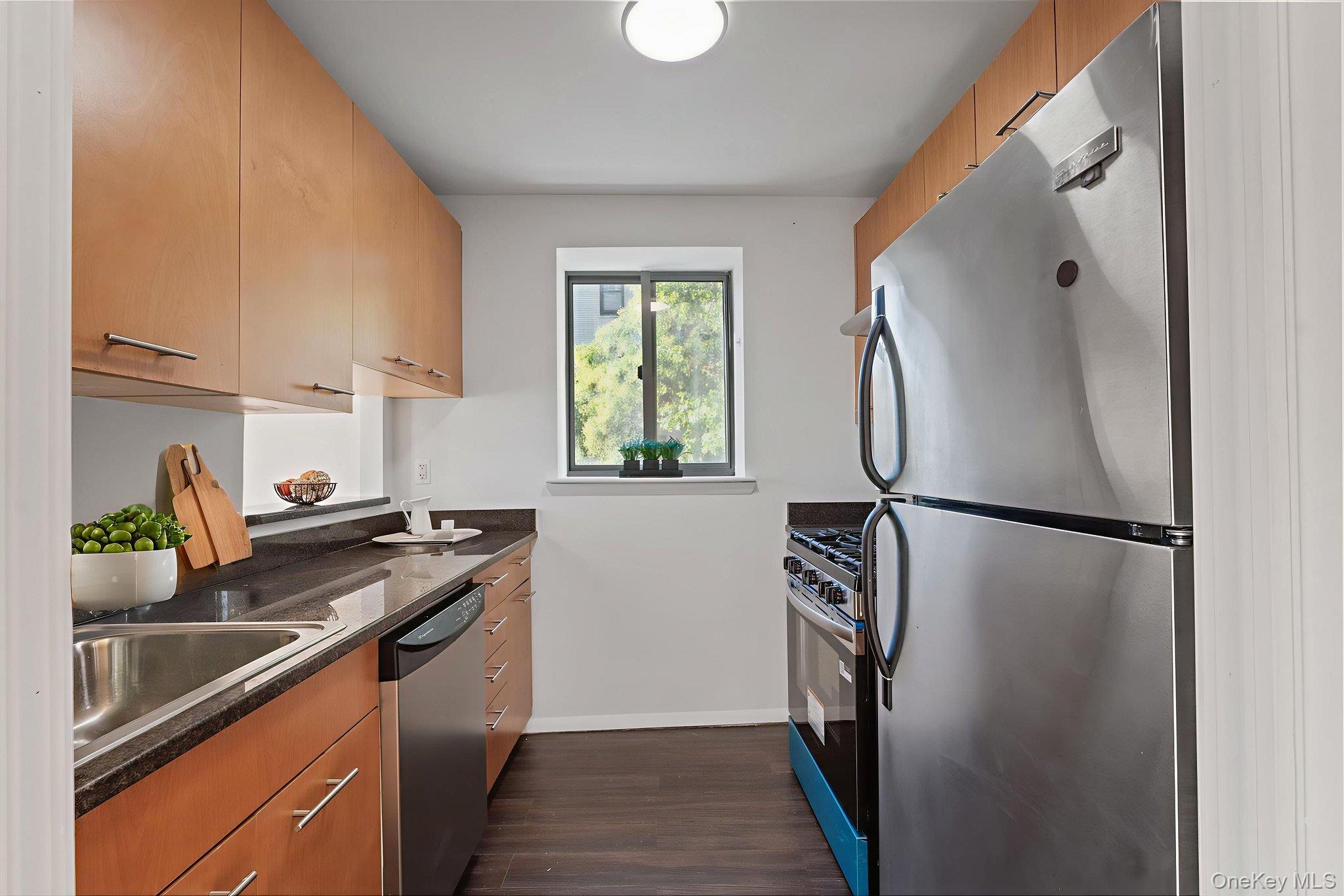 2360 Amsterdam Avenue, Unit 2C Manhattan, NY 10033 - Photo 19 of 29 Kitchen with stainless steel appliances, dark wood-style floors, dark stone counters, and brown cabinets